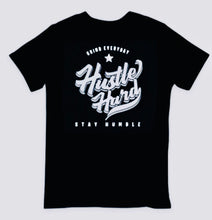 Load image into Gallery viewer, A reminder to hustle daily. Hustle hard and stay humble black and white t-shirt. “Persistently strive, remain modest” - a black and white tee as a daily nudge to keep pushing forward.
